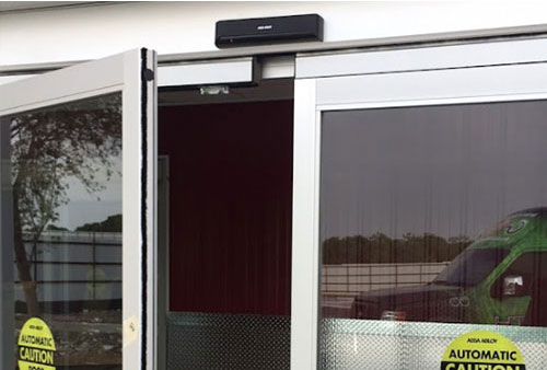 An entry system mounted above an automatic sliding door.